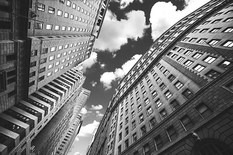 Looking up at a sunny sky with tall buildings all around