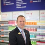 Andy Francis smiles in front of merchandise inside a Boots store.