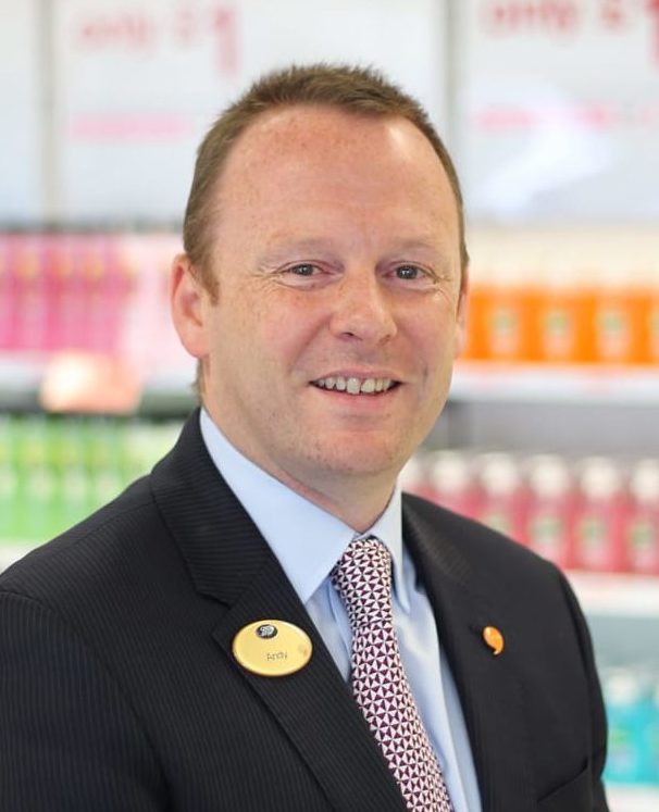 Andy Francis smiles in front of merchandise inside a Boots store.