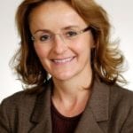 Fiona Adshead in brown jacket smiles at the camera
