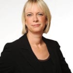 Fiona Ball in a black suit looks at the camera