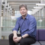 Ian Thomson sits in a light filled atrium