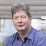 Ian Thomson sits in a light filled atrium