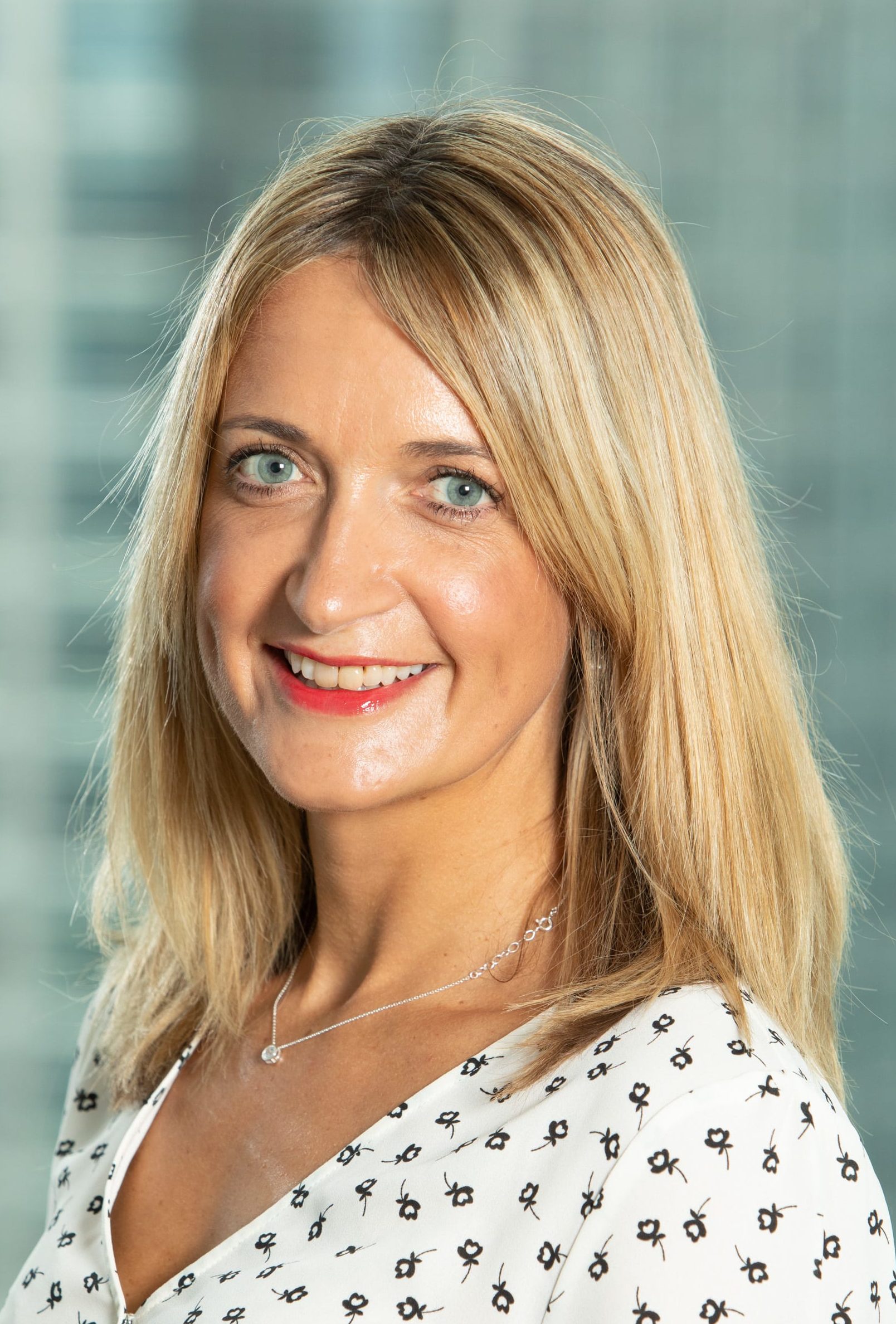 Kirstie Mackey in a white and black patterned top smiles