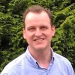 Andrew Griffiths wearing a blue shirt and smiling