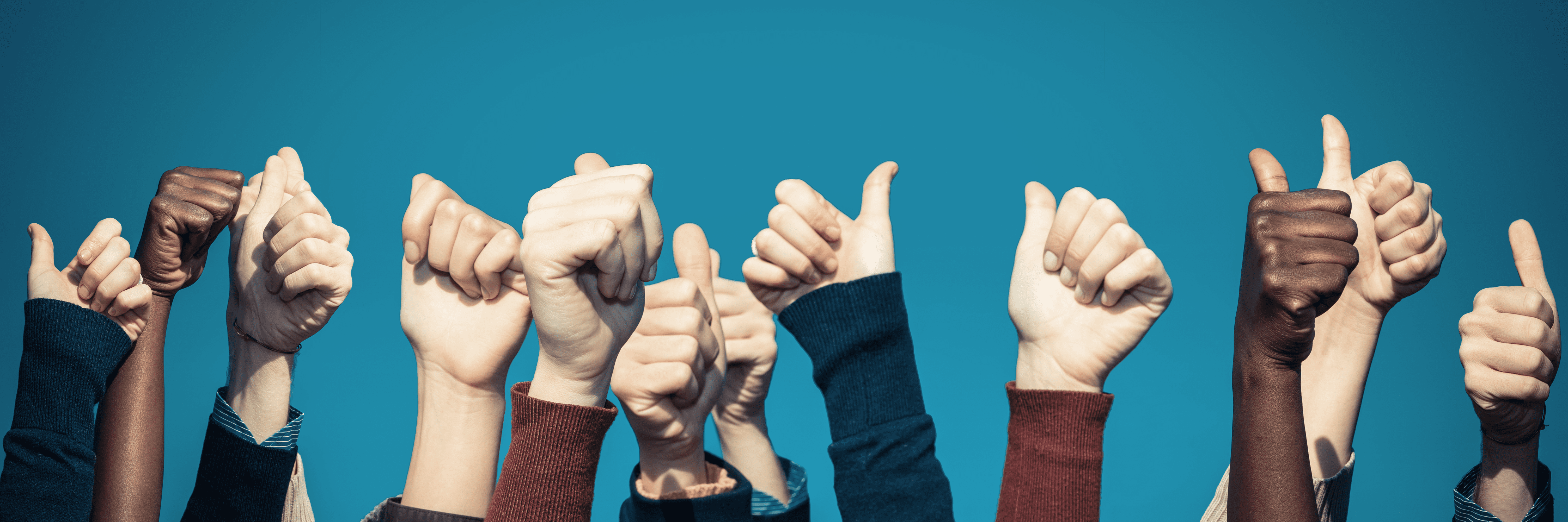 A row of racially diverse hands point skywards with thumbs raised