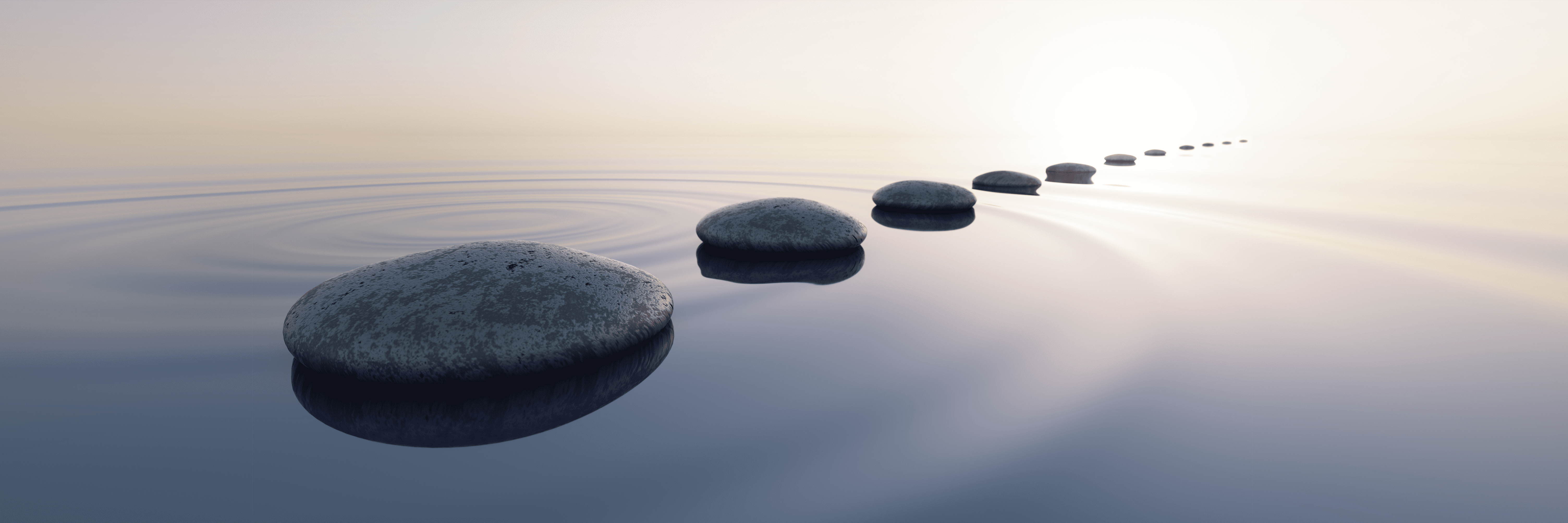A calm and tranquil lake with large stones dissapearing onto the horizon