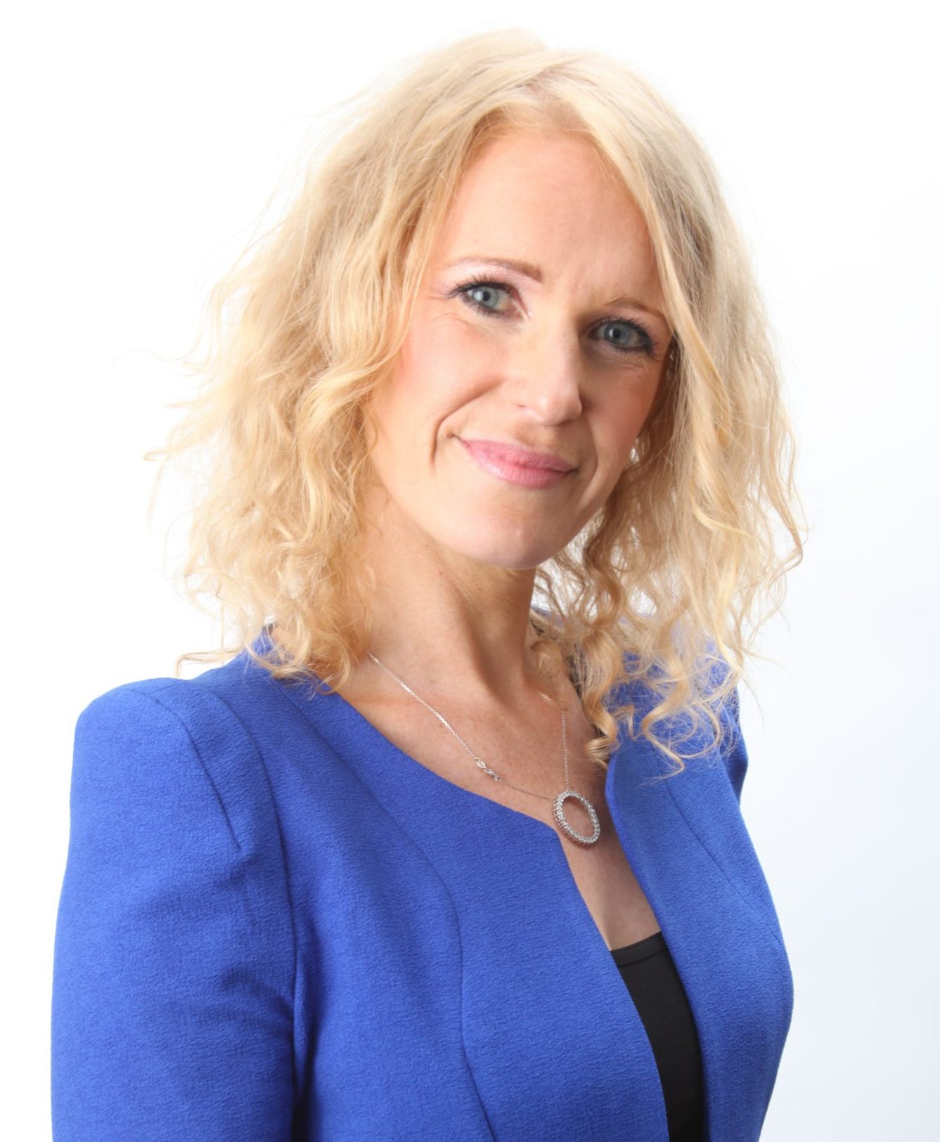 Lucy Becque wearing a sapphire blue suit smiles into the camera.