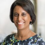 Vidhya wearing a flowery top, smiles towards the camera