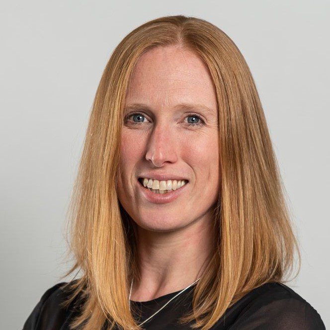 Cat wearing a black top, smiles towards the camera