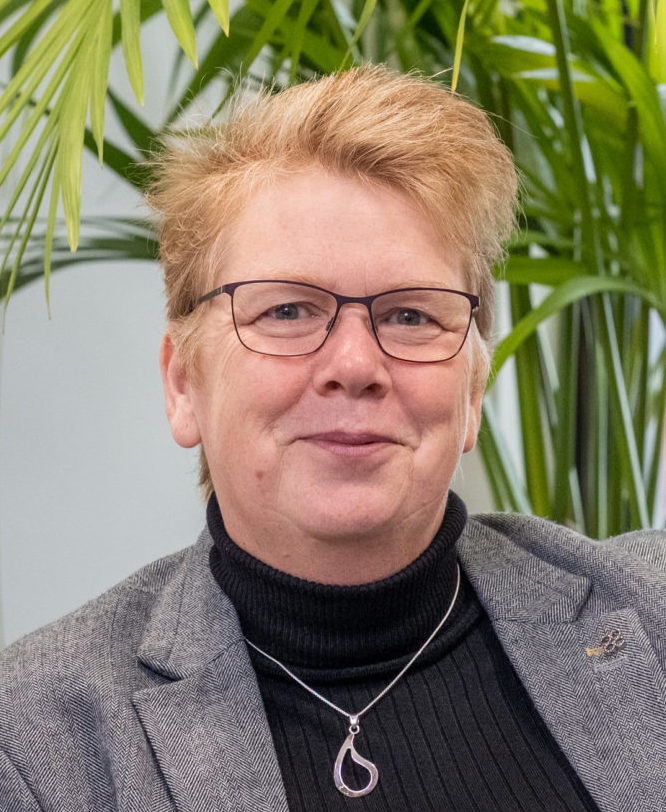 Suzanne wearing black spectacles, smiles towards the camera