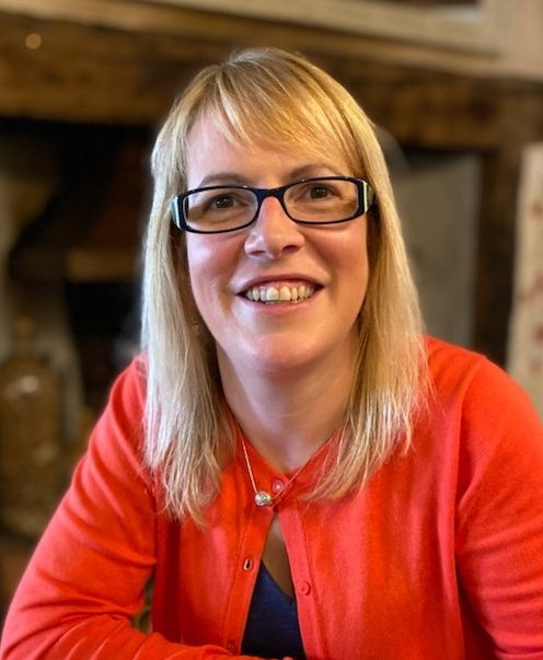 Suzanne wearing black spectacles, smiles towards the camera