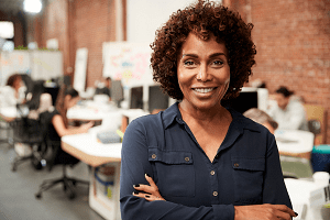 A black woman standing in a office depicting the age at work campaign one of the supporting people initiatives from BITC. 