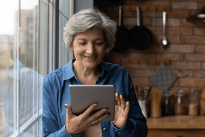 A  older woman holding a computer tablet, depicting the Clicksilver campaign one of the supporting people initiatives from BITC. 