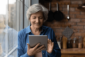 A older woman holding a computer tablet, depicting the Clicksilver campaign one of the supporting people initiatives from BITC.