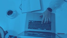 An image of a laptop from above with a hand touching the laptop working on a responsible business strategy.