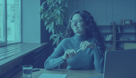 An image of a person smiling staring out the window at their desk