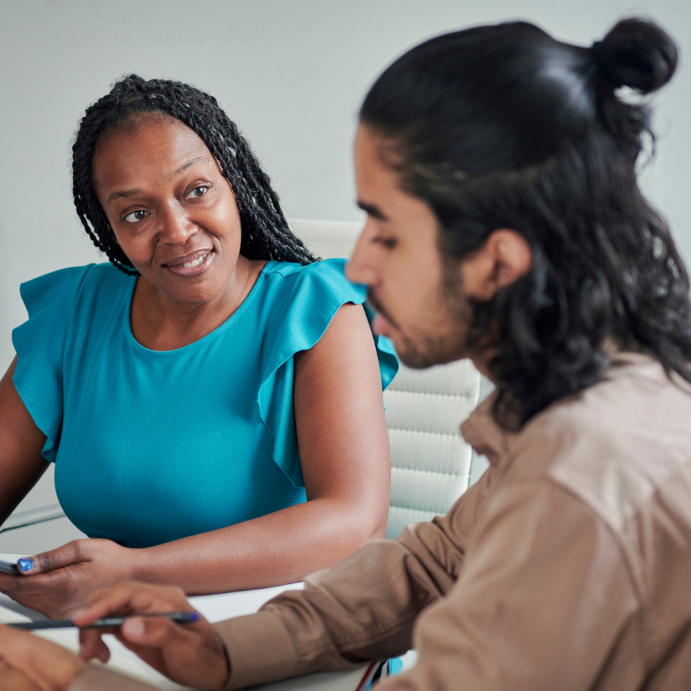 An image of two people sitting at a desk talking