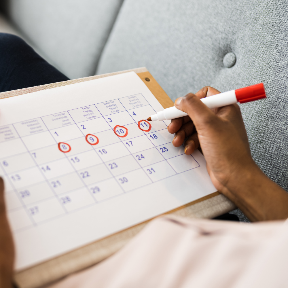 An image of someone holding a calendar looking at dates and holding a pen to the paper.