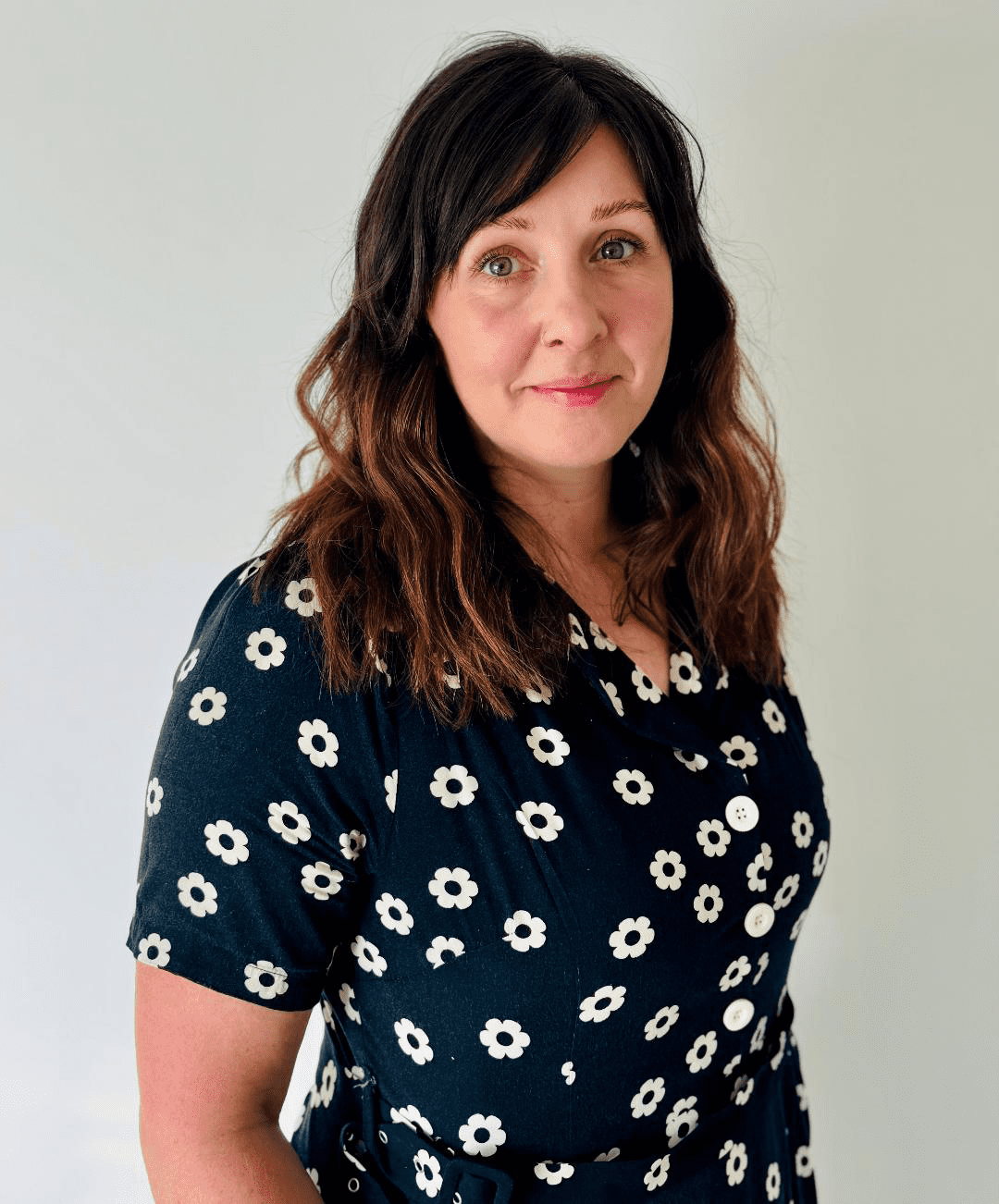 Simone Devinett looking at camera, standing against a white plain background.